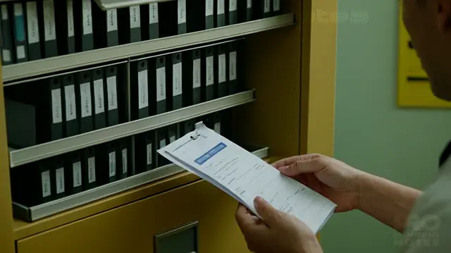 A patient opening a medical file cabinet, holding a copy of their mental health records, surrounded by confidentiality signage and a computer displaying electronic records management software
